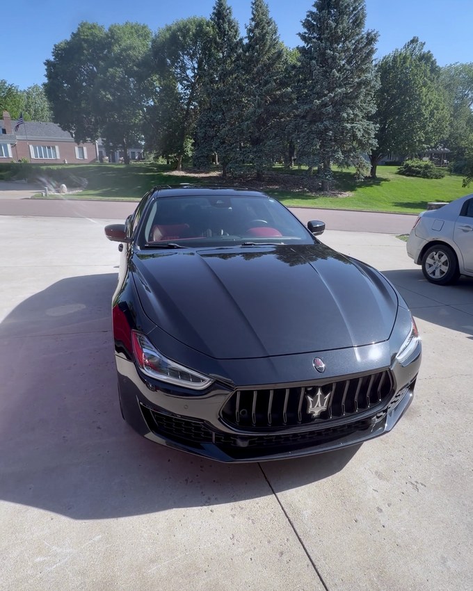 A black Maserati saloon with red brake calipers, photographed outside on a clear day.