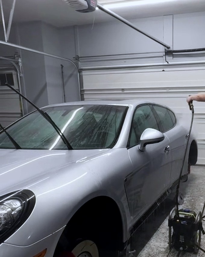A silver Porsche raised with a wheel removed and the brake disc and caliper exposed.
